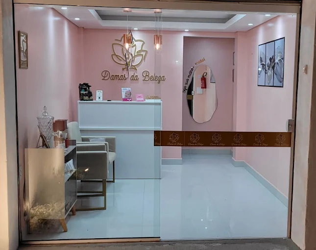 Vitrine de vidro da Damas da Beleza, mostrando a recepção com poltronas, balcão e a faixa dourada na parede.