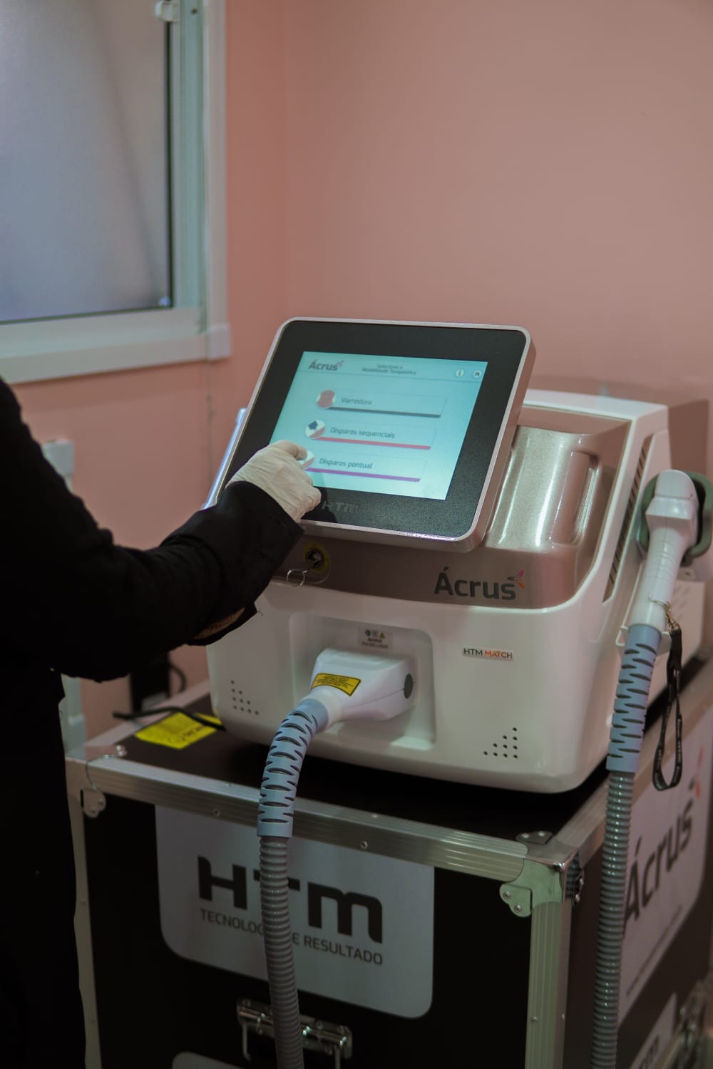 Profissional de luva ajustando na tela do laser a modalidade de disparo.